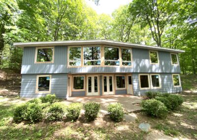 custom contemporary home with blue painted wood sidings, large windows and wood sided glass door